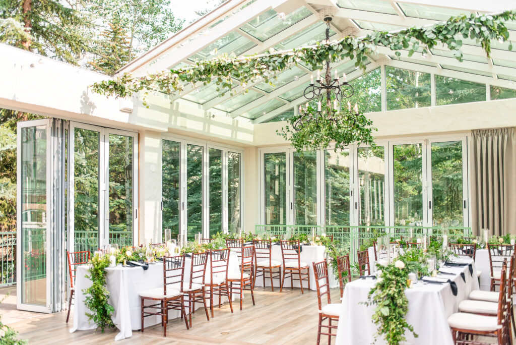 Wide shot of an outdoor green house like reception room decorated with greenery at the Sonnenalp Hotel in Vail, Colorado.