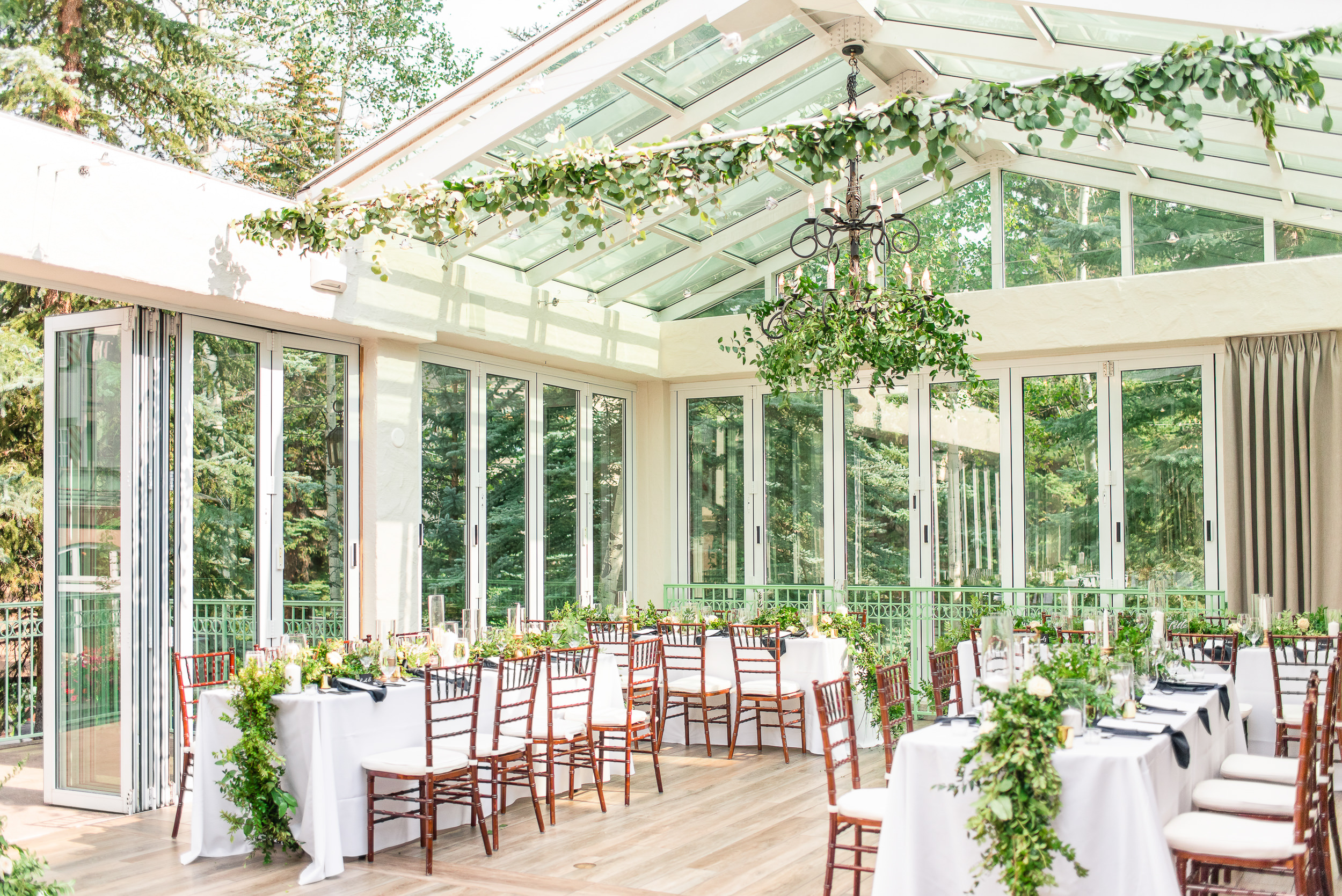 Wide shot of an outdoor green house like reception room decorated with greenery at the Sonnenalp Hotel in Vail, Colorado.