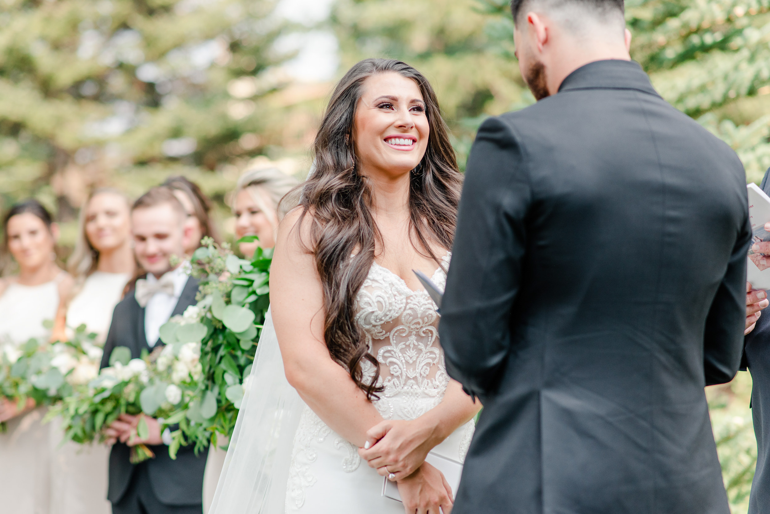 During an outdoor wedding ceremony at the Sonnenalp Hotel in Vail a bride smiles at her Groom as he reads his vows to her.