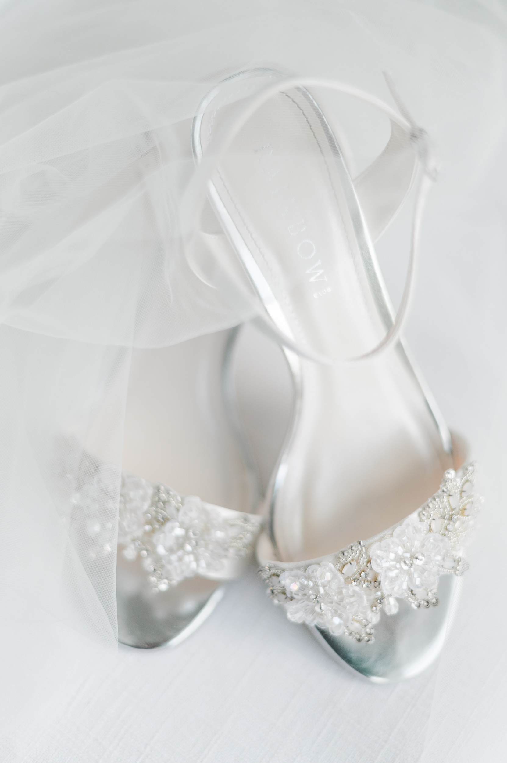 Detail image of a bride's wedding shoes with her veil laying over them.