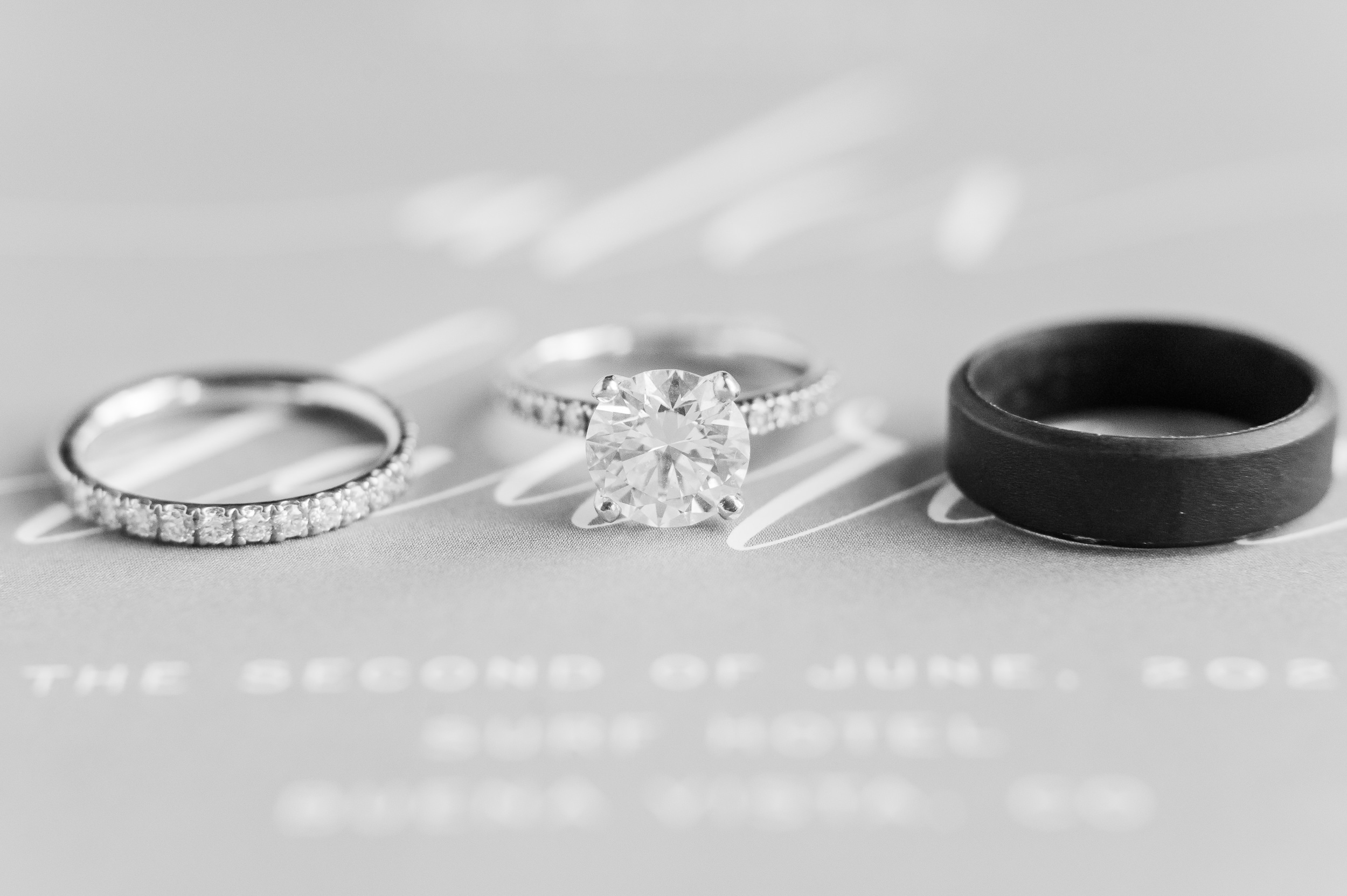 Close up photograph of a bride and groom's wedding rings laying on their invitation.
