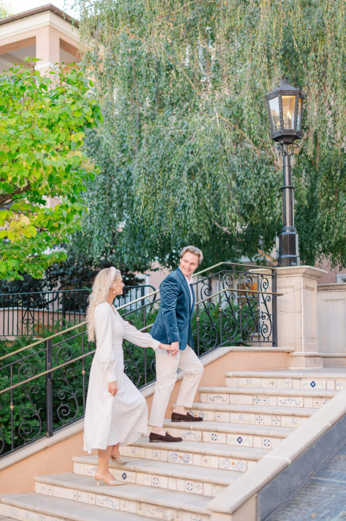 A man leads a woman up a set of stairs during their engagement photos at the Broadmoor Hotel in Colorado Springs.