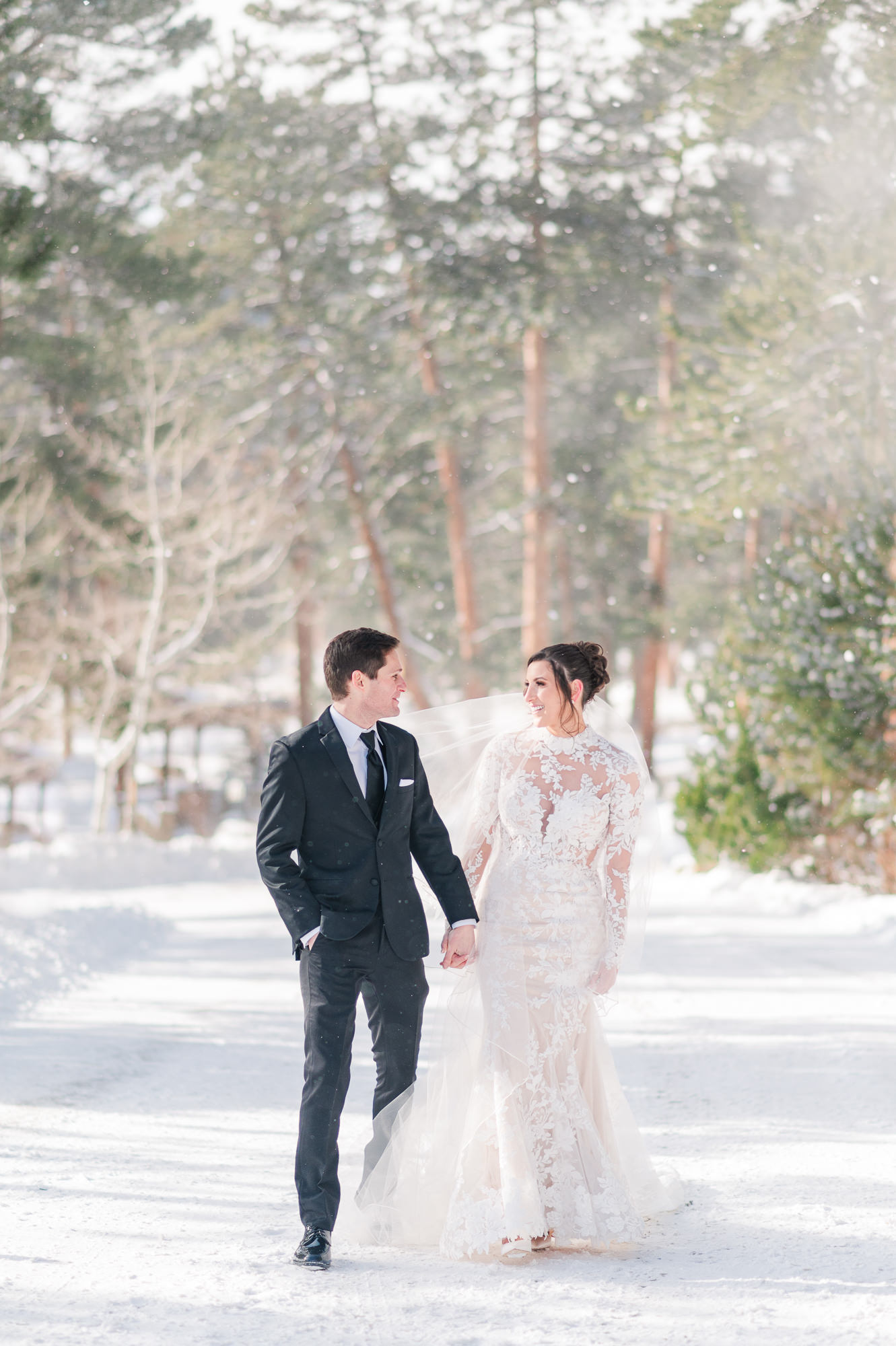 Bride and Groom walk hand in hand down the snowy road on their wedding day at Della Terra Chateau in Estes Park, Colorado.