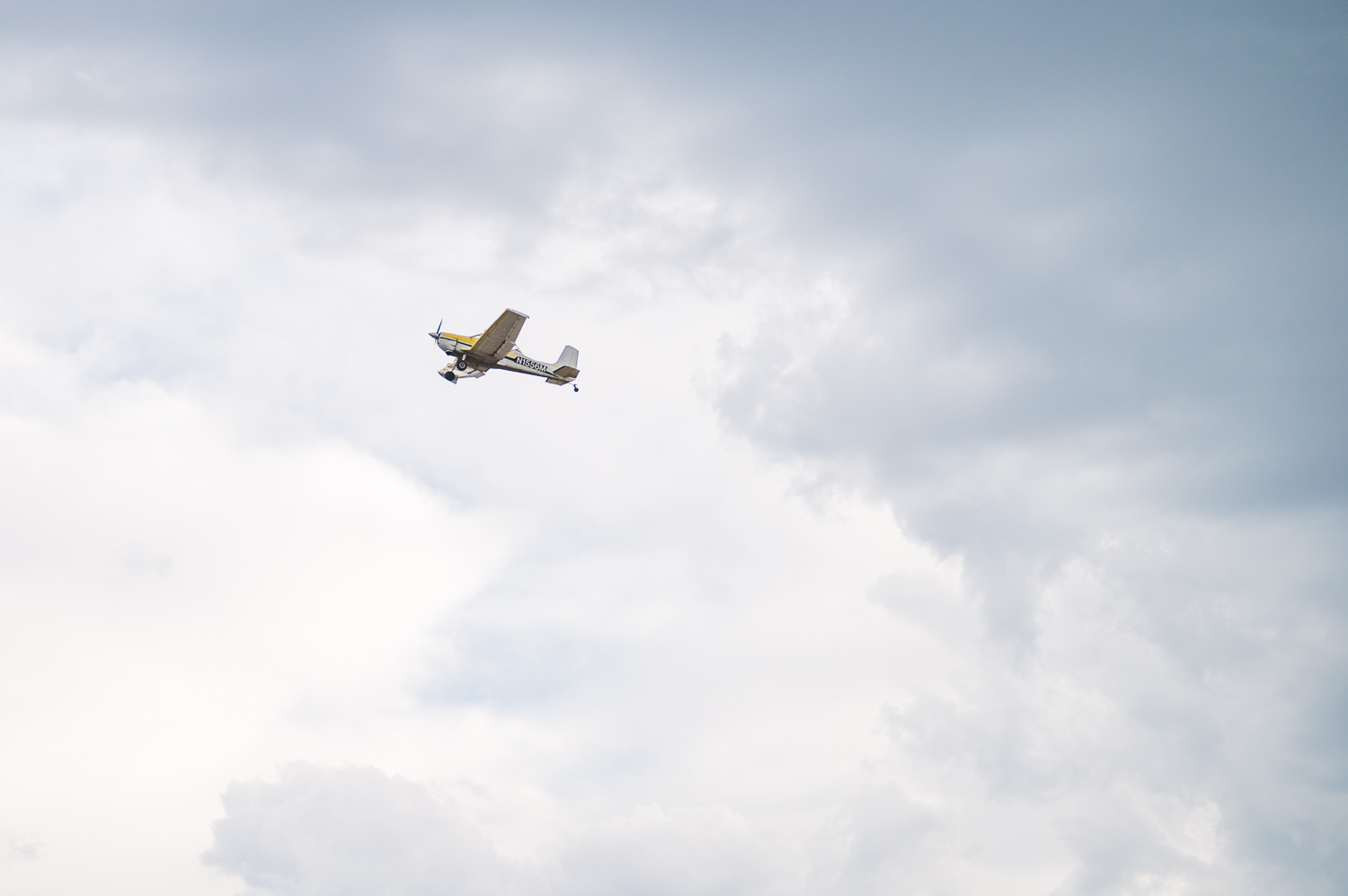 A small airplane flies in a cloudy sky.