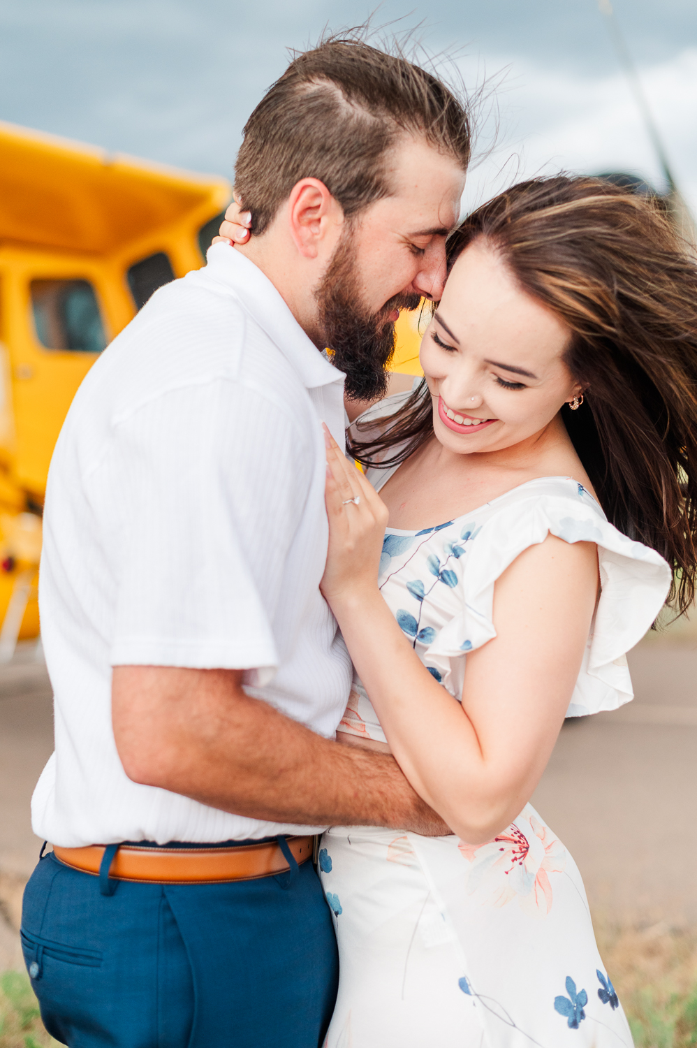 A couple snuggles in front of an airplane for their engagement photo.