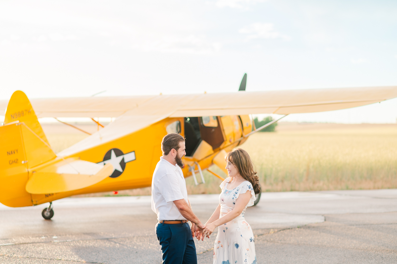 Couple dances in front of an airplane for their engagement photos.