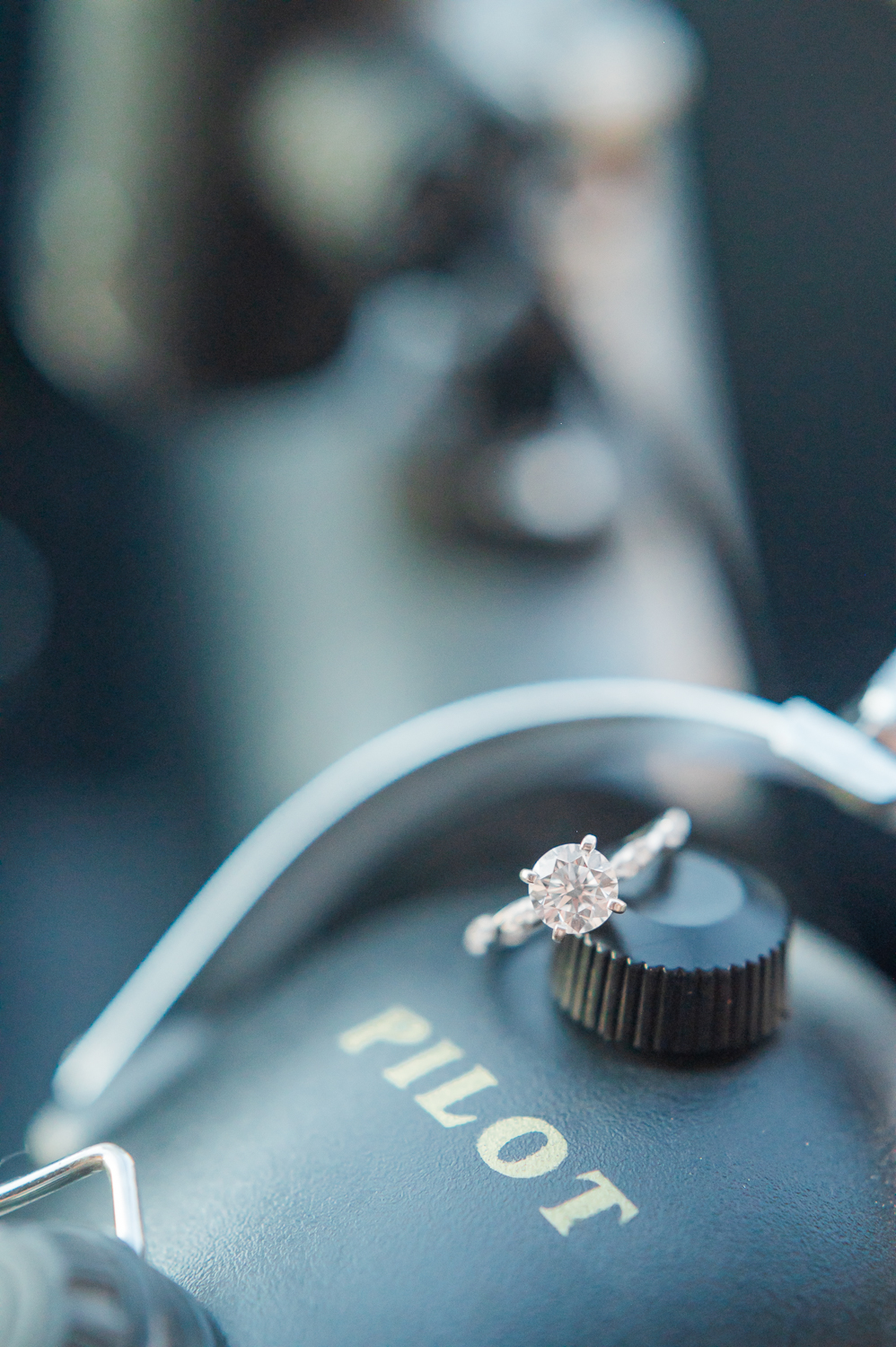 Close up of a diamond engagement ring on a pilot's headset.